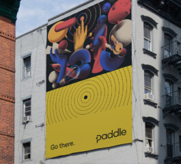 An out of home advertisement for Paddle, showcasing its different visual identity elements. 